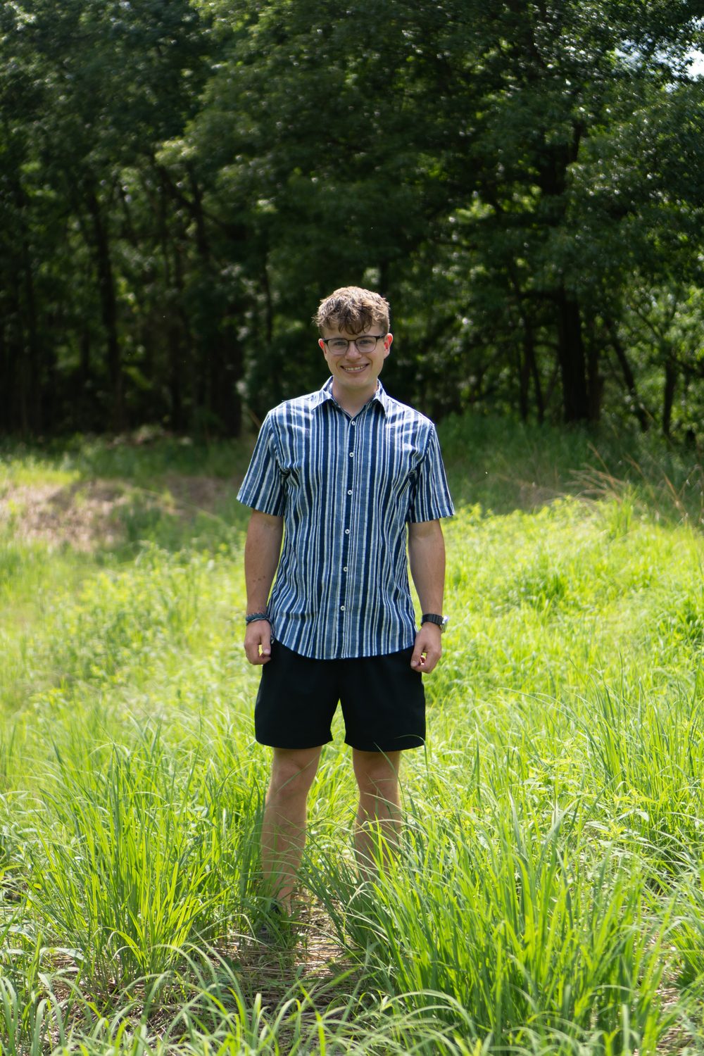 Senior portrait, standing in a sunlit field