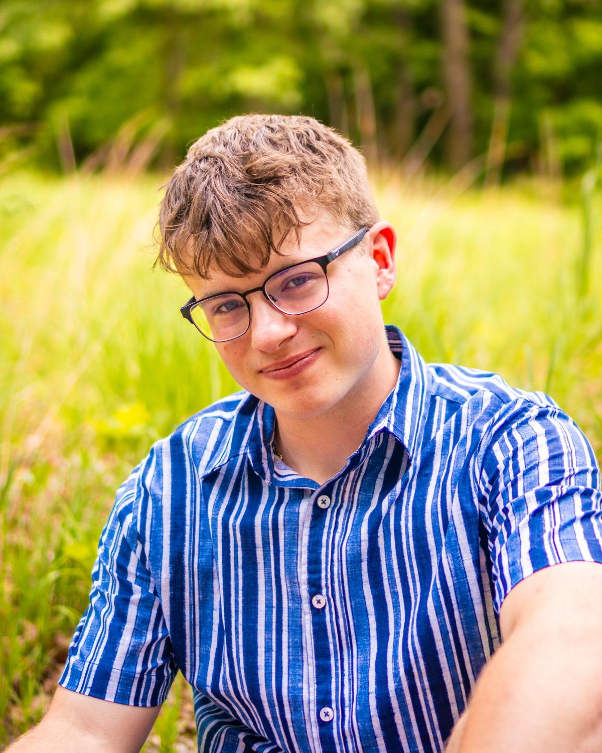 Senior portrait close-up, seated in tall grass